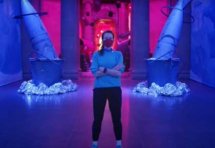Photograph of artist Heather Phillipson standing in the Duveen Galleries at Tate Britain