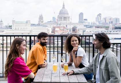 Four people sitting on a terrace with St Pauls Cathedral behind them