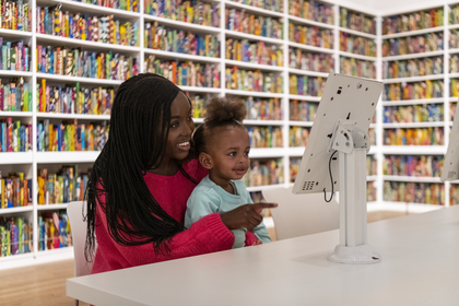 A parent and child in a gallery looking at a screen